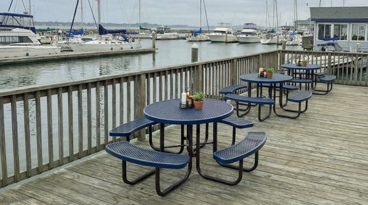 3 blue round picnic tables at a marina restaurant next to the water and boats