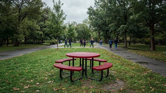 Round red picnic table in a park on a rainy day with people walking in the background