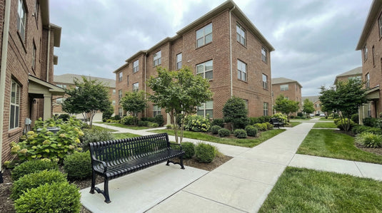 A black metal bench on a trail at an apartment complex 